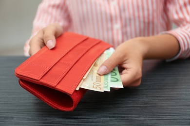 Photo of Woman putting Euro banknotes in wallet, closeup