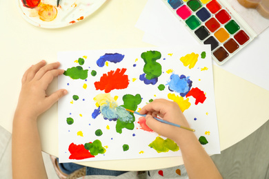 Photo of Little child painting at light table, top view