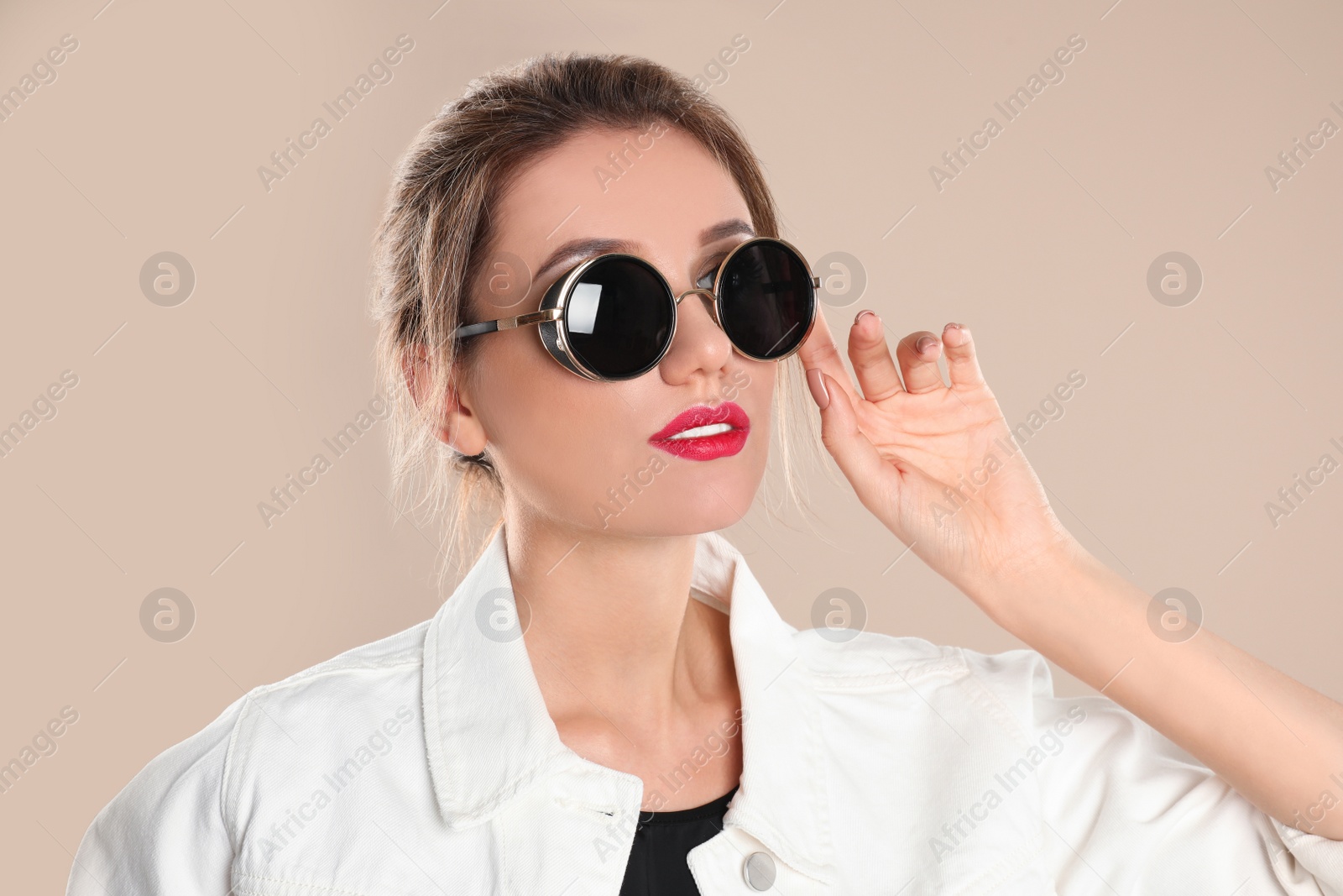 Photo of Young woman wearing stylish sunglasses on beige background