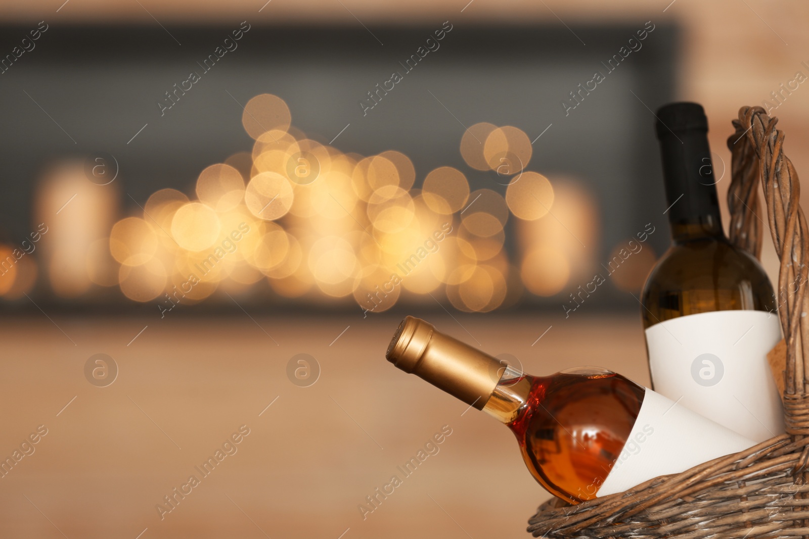 Photo of Wicker basket with bottles of wine against blurred background, closeup. Space for text