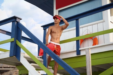 Photo of Handsome lifeguard with life buoy on watch tower