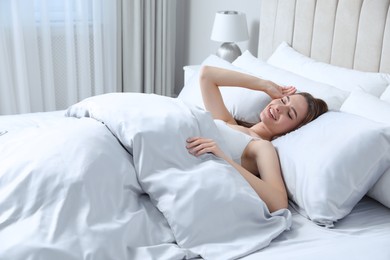 Young woman awaking in comfortable bed with silky linens