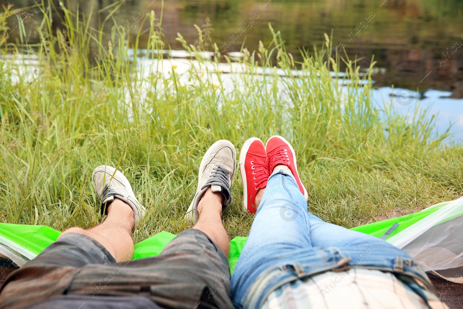 Photo of Young couple resting near pond. Camping season