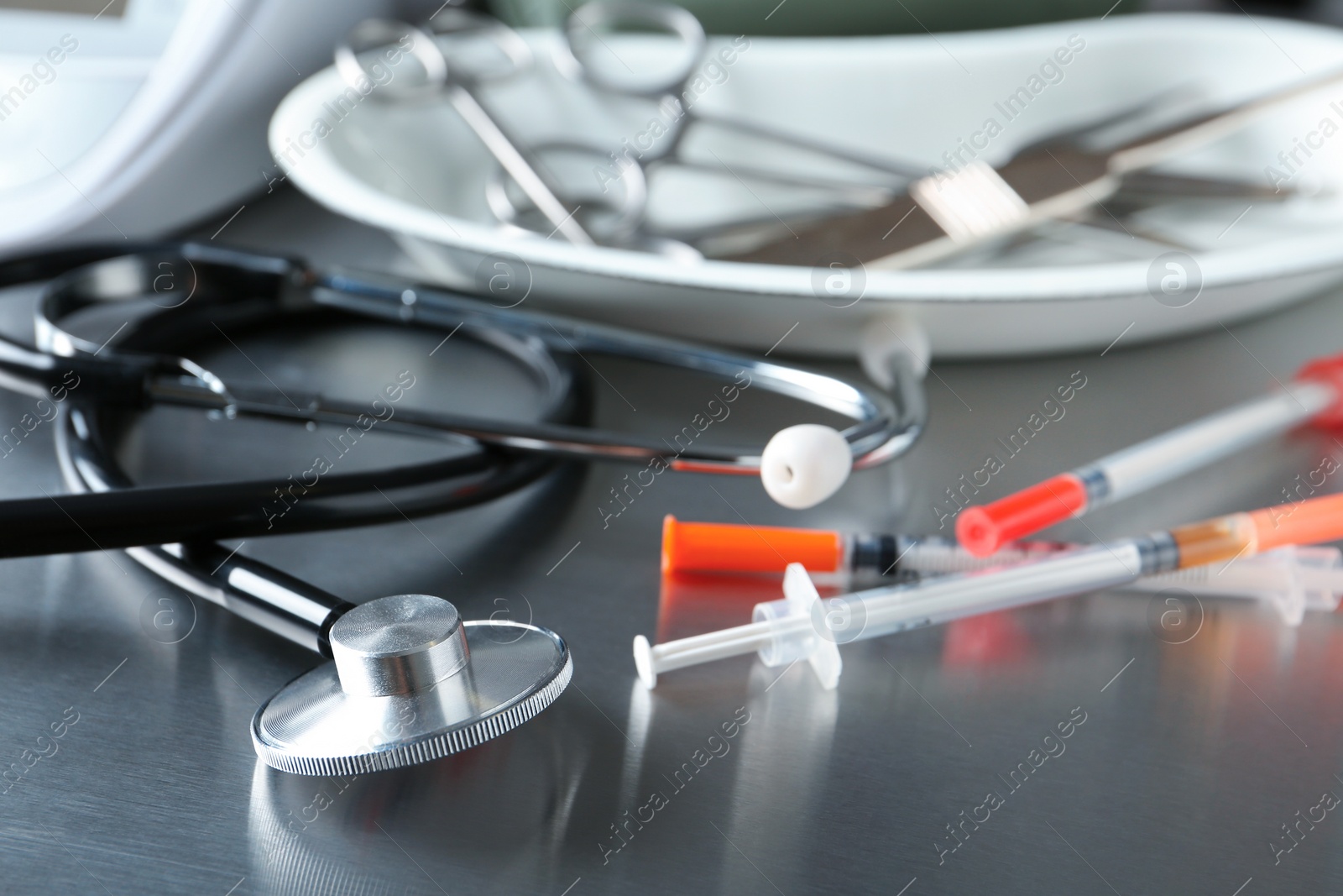 Photo of Stethoscope and syringes on grey table. Medical objects