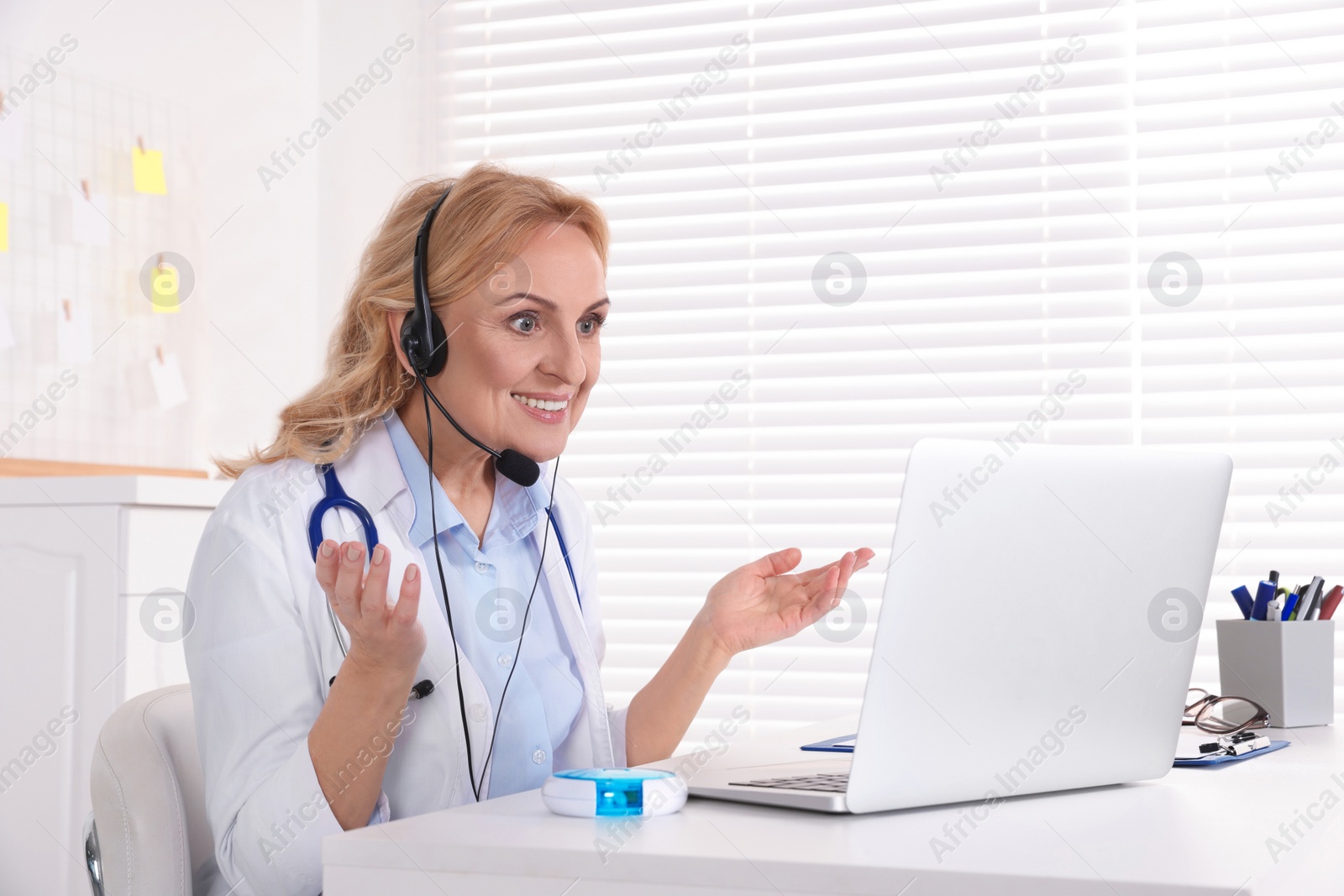 Photo of Doctor with laptop and headphones consulting patient in clinic. Online medicine concept