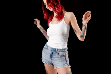 Photo of Beautiful woman with tattoos on body against black background