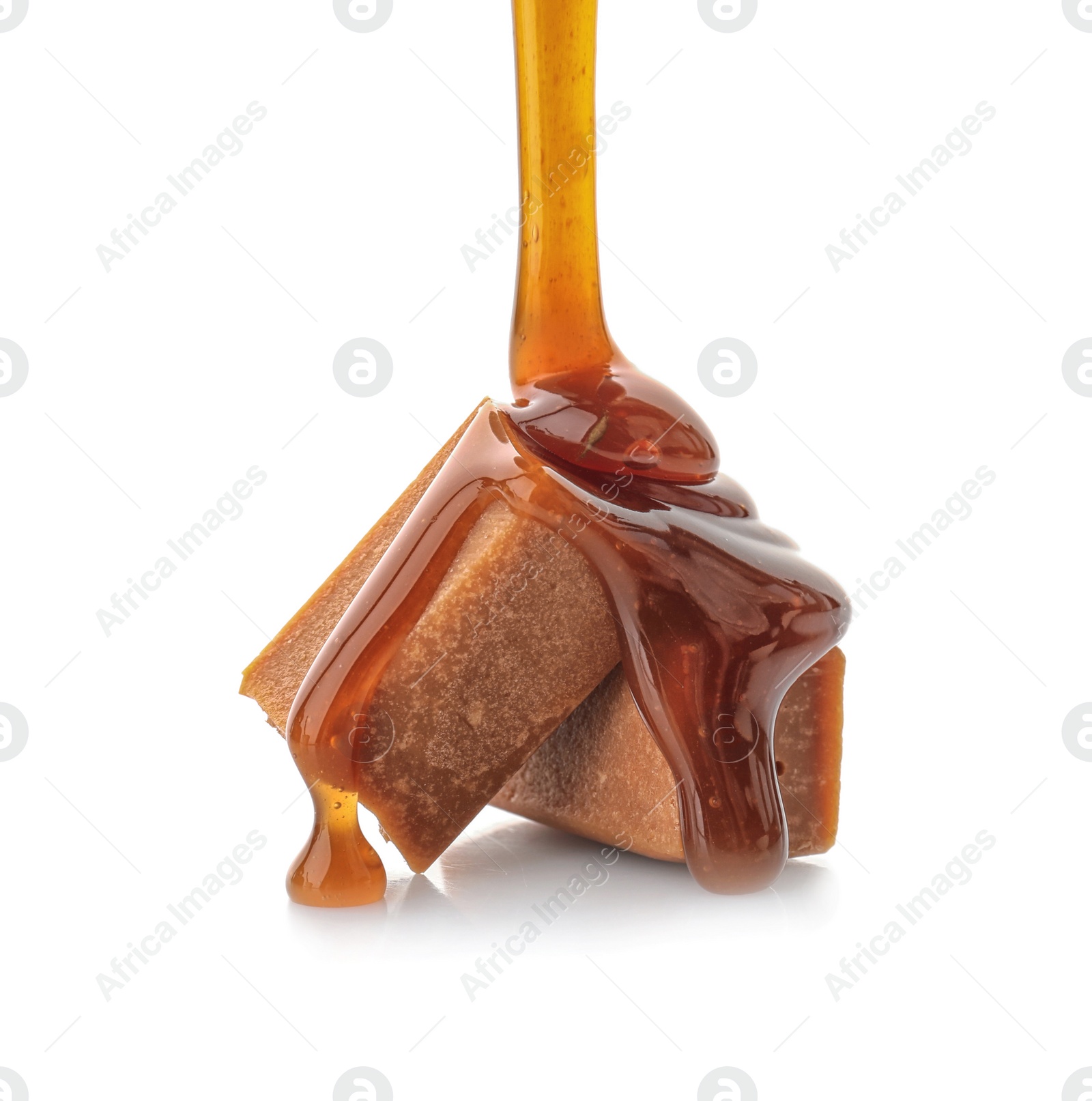 Photo of Pouring caramel sauce onto delicious candies on white background