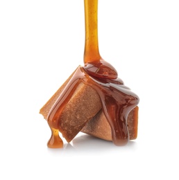 Photo of Pouring caramel sauce onto delicious candies on white background