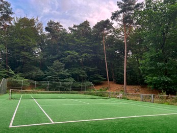 Photo of Tennis court with green grass and net outdoors