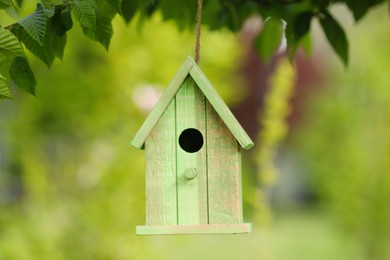 Photo of Green bird house hanging on tree outdoors