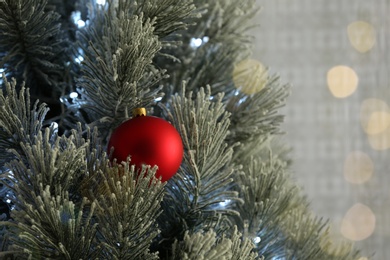 Photo of Beautiful Christmas tree decorated with festive lights and red ball, closeup