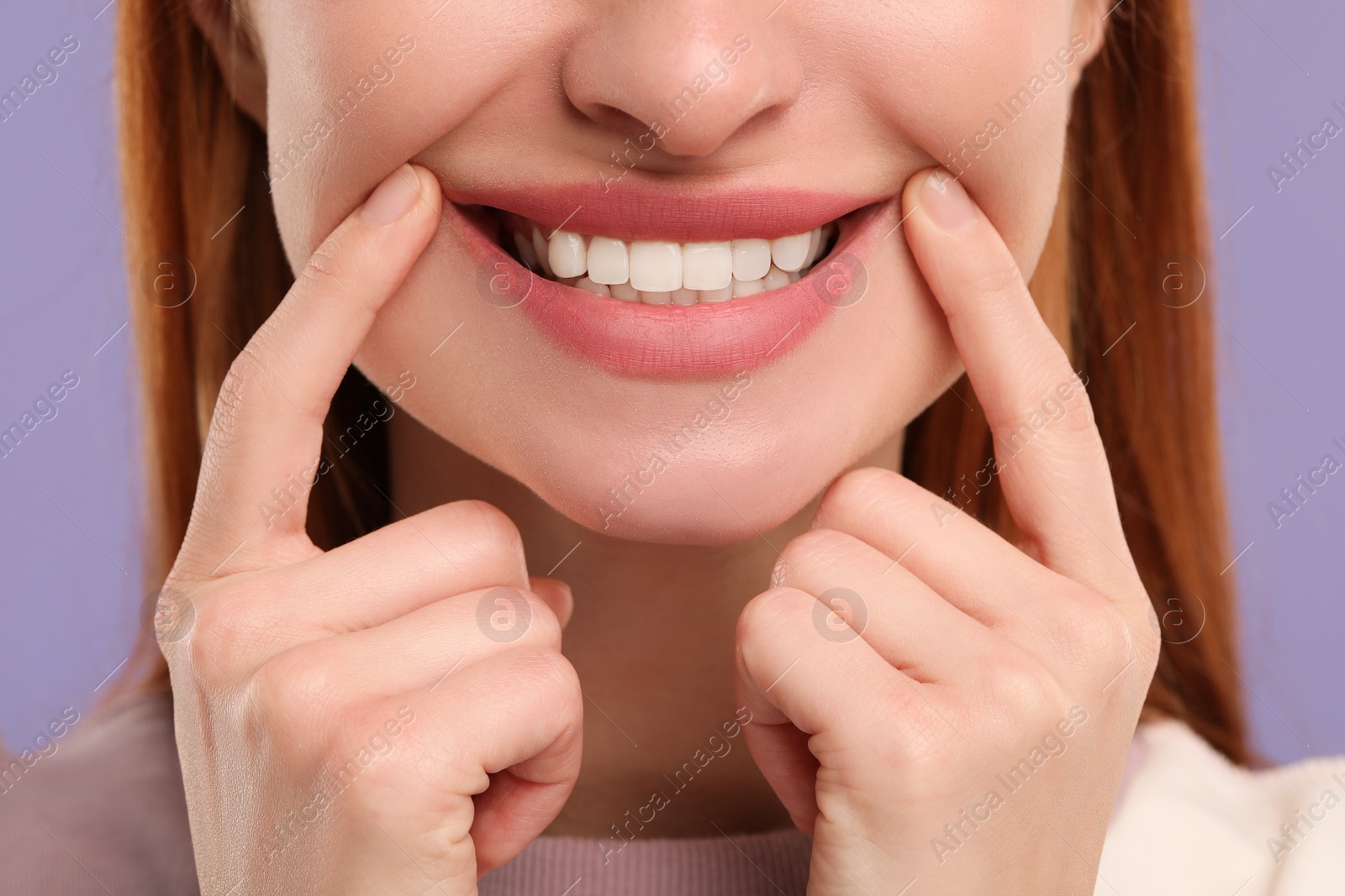 Photo of Woman showing her clean teeth and smiling on violet background, closeup