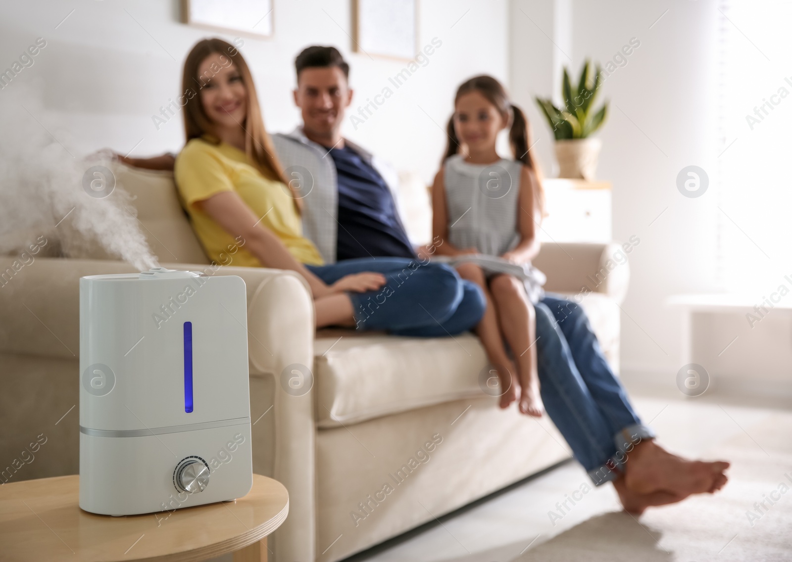 Photo of Modern air humidifier and blurred family on background