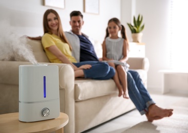 Modern air humidifier and blurred family on background