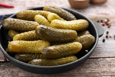 Photo of Pickled cucumbers in pan on wooden table, closeup