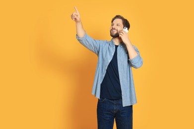 Man talking on smartphone against orange background