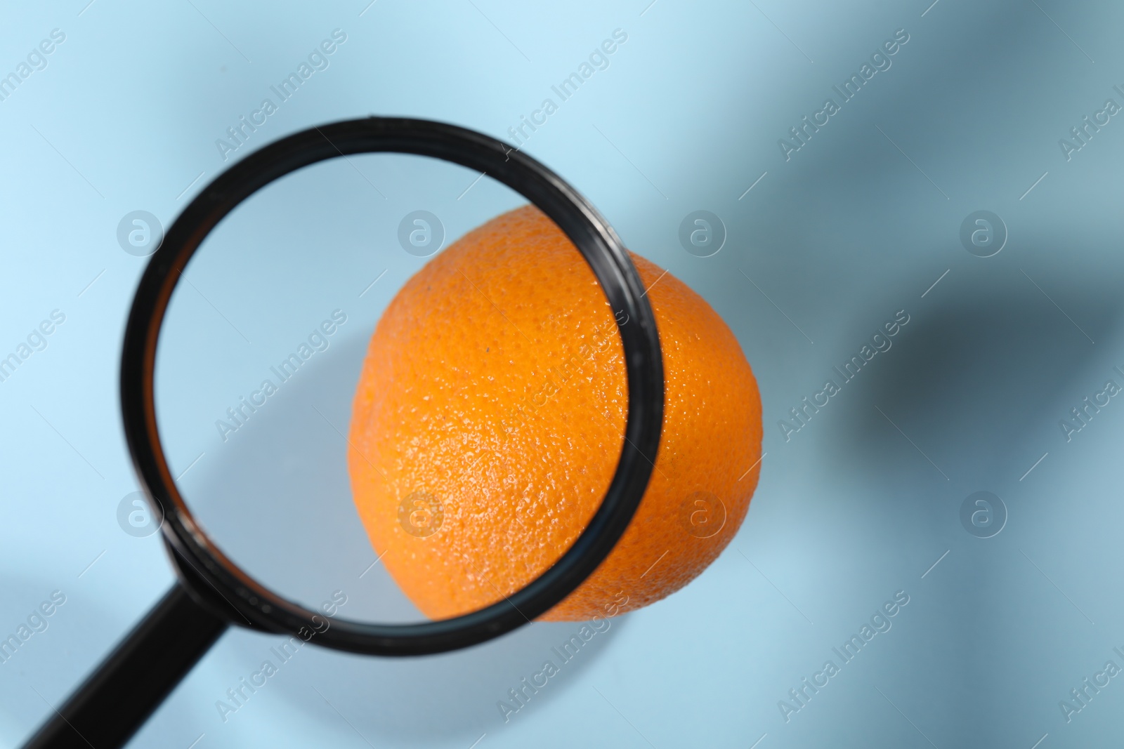 Photo of Cellulite problem. Zoomed orange peel on light blue background, top view through magnifying glass