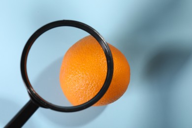 Photo of Cellulite problem. Zoomed orange peel on light blue background, top view through magnifying glass