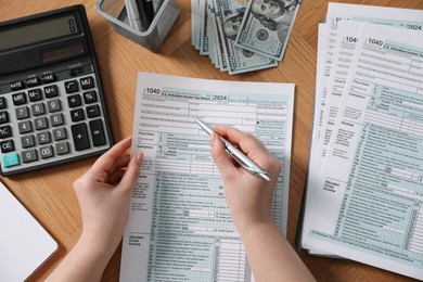 Payroll. Woman working with tax return forms at wooden table, top view