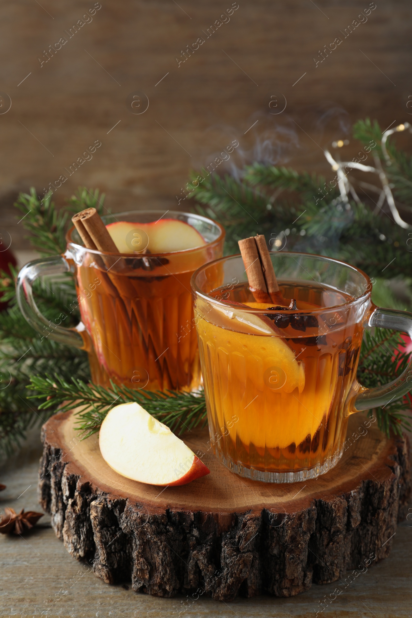 Photo of Hot mulled cider, ingredients and fir branches on wooden table