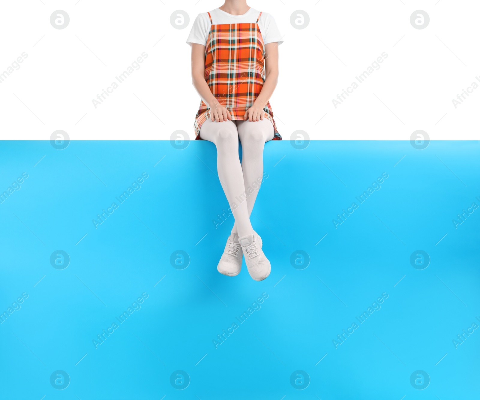 Photo of Woman wearing white tights and stylish shoes sitting on color background, closeup