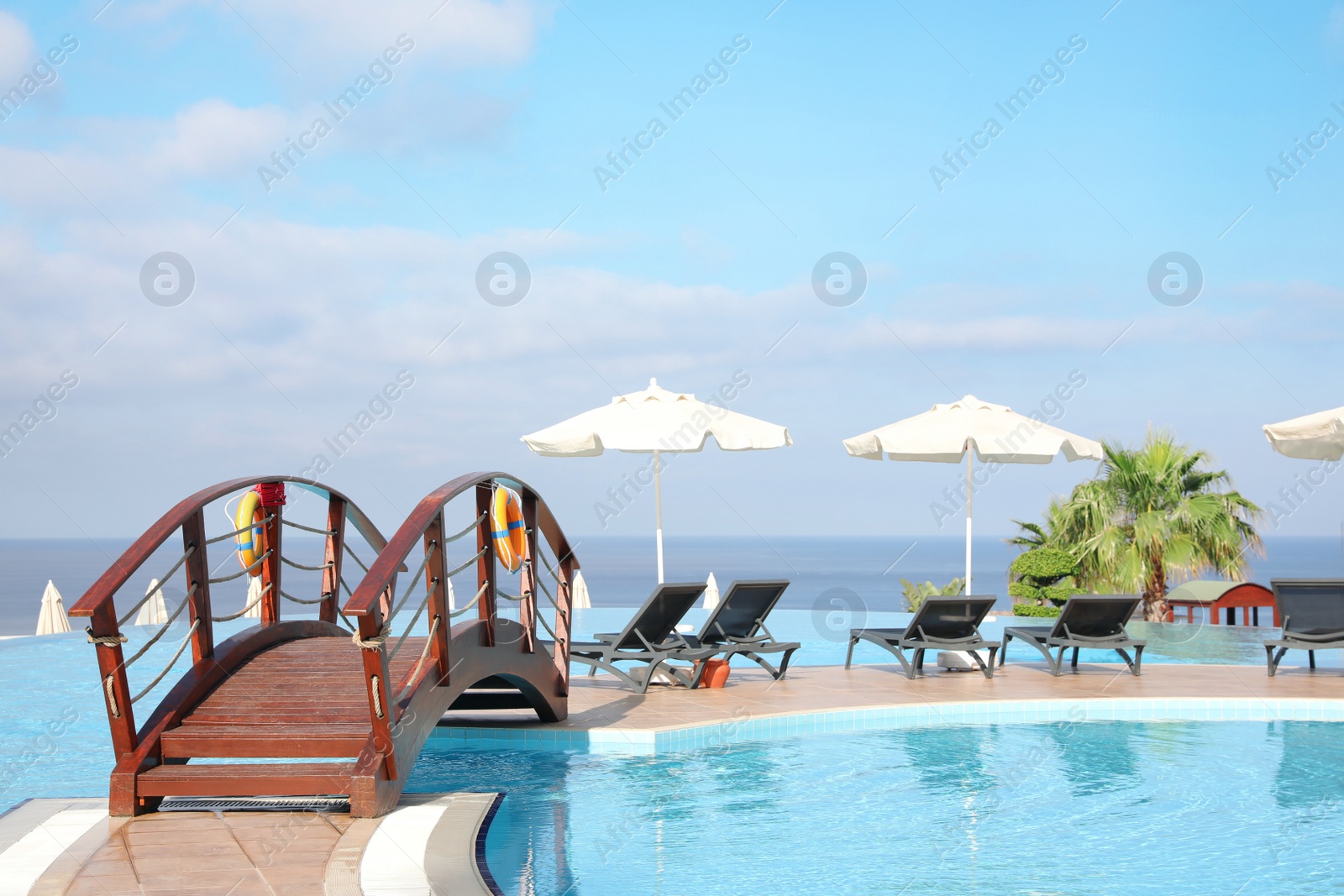 Photo of Chaise longues and beach parasols near outdoor swimming pool at resort