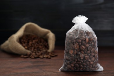 Scented sachet with coffee beans on wooden table, closeup. Space for text