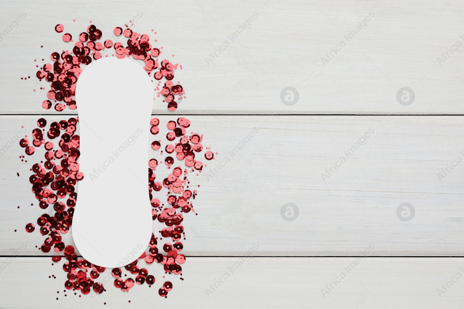 Photo of Sanitary pad surrounded by red sequins on white wooden background, flat lay and space for text. Menstrual cycle