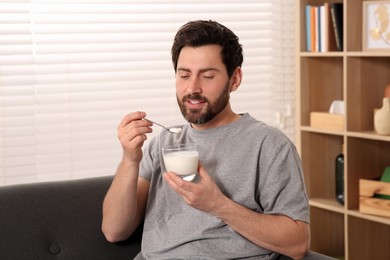 Photo of Handsome man with delicious yogurt at home