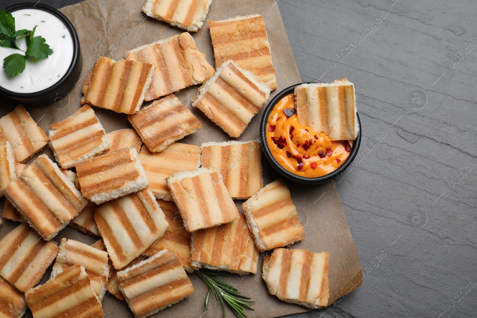 Photo of Delicious pita chips and sauce on black table, top view