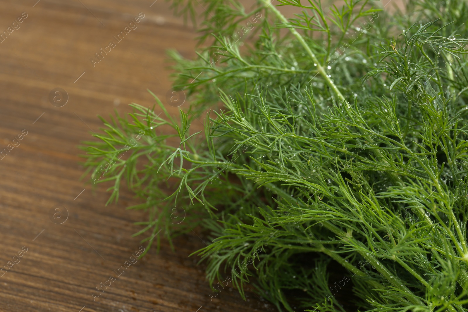 Photo of Fresh green dill on wooden table, closeup
