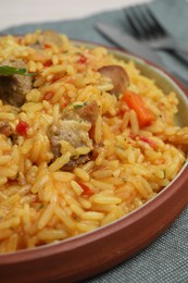 Photo of Delicious pilaf with meat on grey tablecloth, closeup