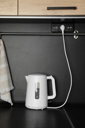 Photo of Modern electrical kettle on black countertop in kitchen