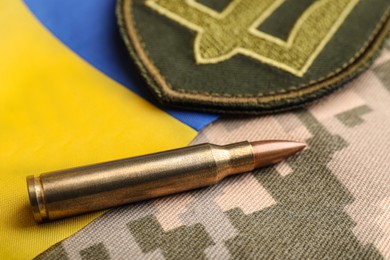 Bullet, Ukrainian flag and military patch on pixel camouflage, closeup
