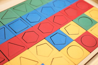 Wooden puzzle with different geometric shapes and colors on table, closeup. Montessori toy