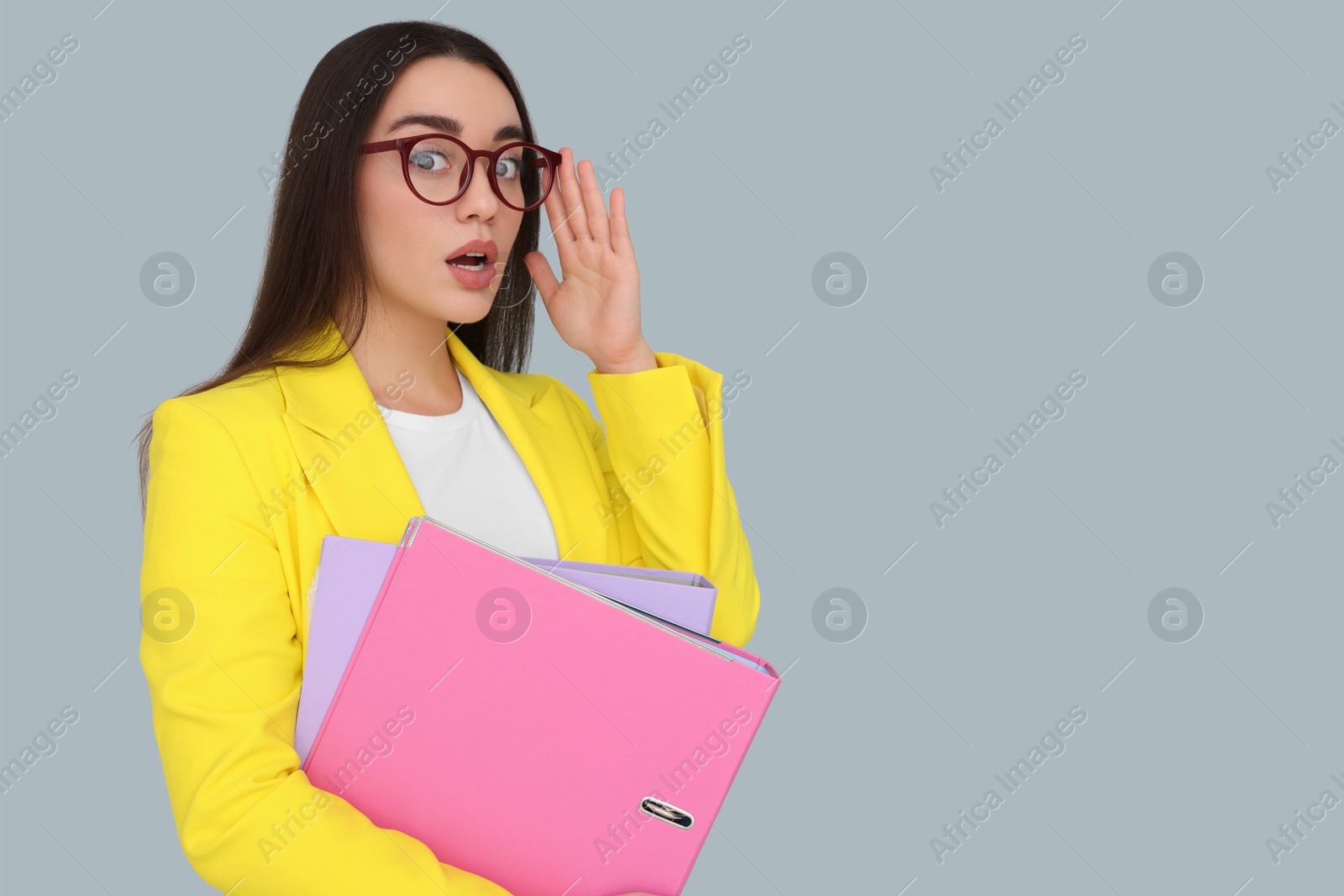 Photo of Young female intern with eyeglasses and folders on grey background, space for text