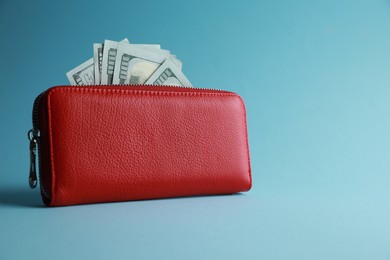 Photo of One stylish leather purse with money on light blue background. Space for text