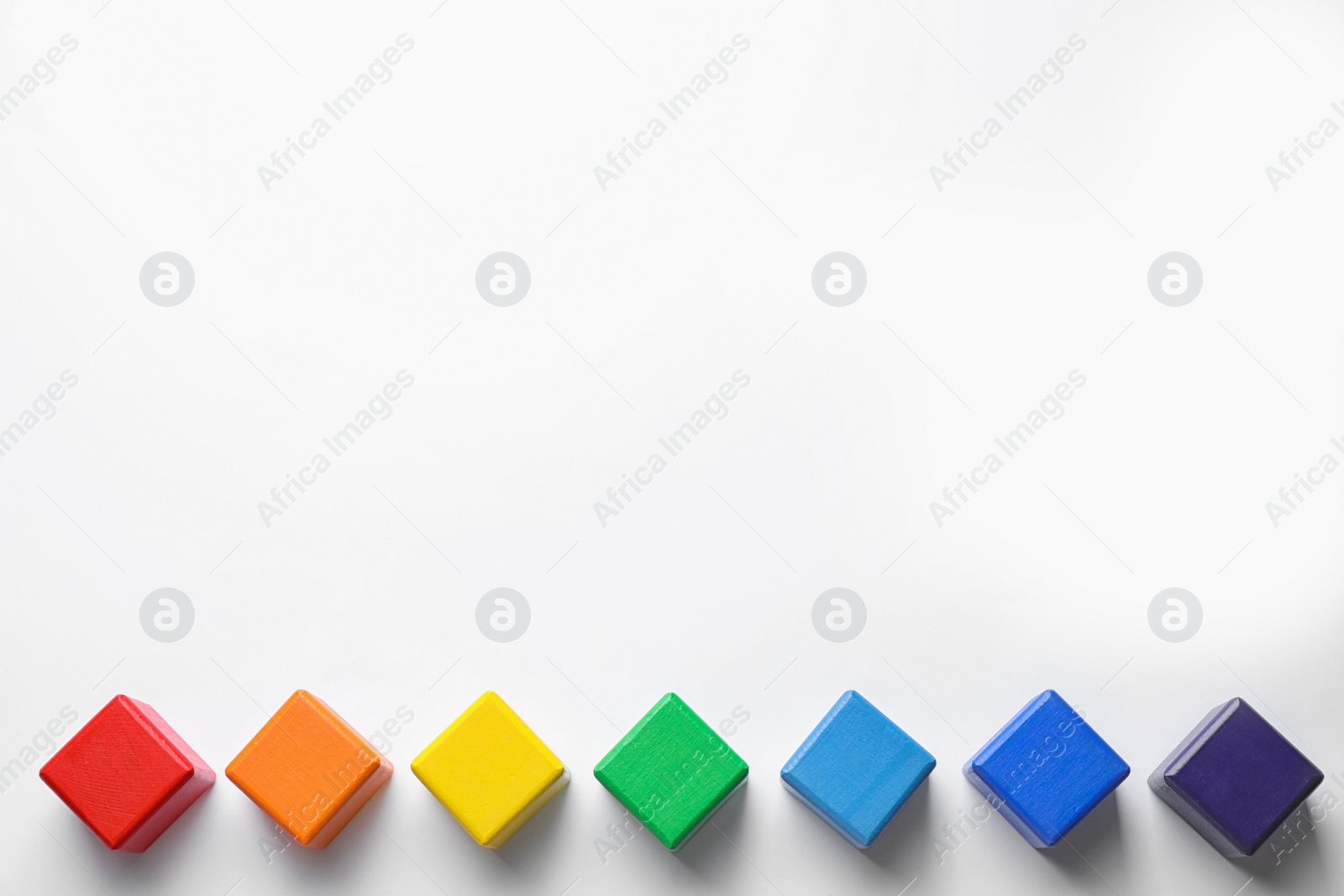 Photo of Bright wooden cubes on white background, top view. Rainbow colors