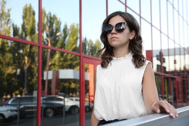 Young businesswoman near modern building on city street