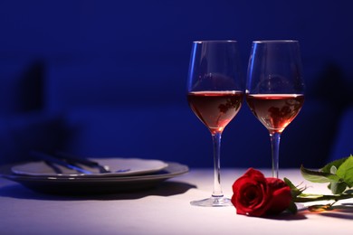 Photo of Beautiful table setting with glasses of wine and rose in dark room. Romantic dinner for Valentine's day