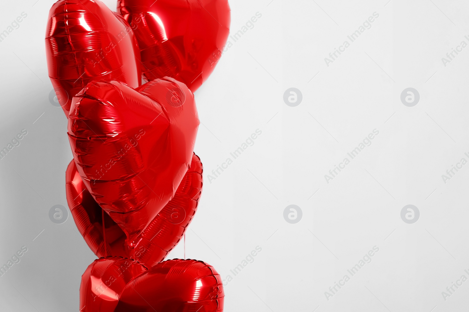 Photo of Many red heart shaped balloons on white background, closeup. Space for text