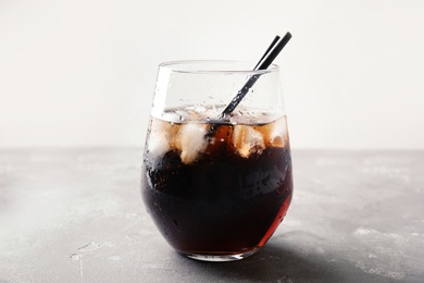 Photo of Glass of refreshing cola with ice on grey table