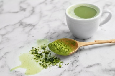 Photo of Cup of fresh beverage and spoon with powdered matcha tea on table