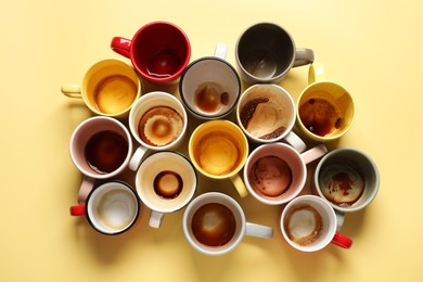 Photo of Many dirty cups after drinking coffee on yellow table, flat lay