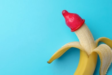 Photo of Banana with condom on light blue background, top view and space for text. Safe sex concept