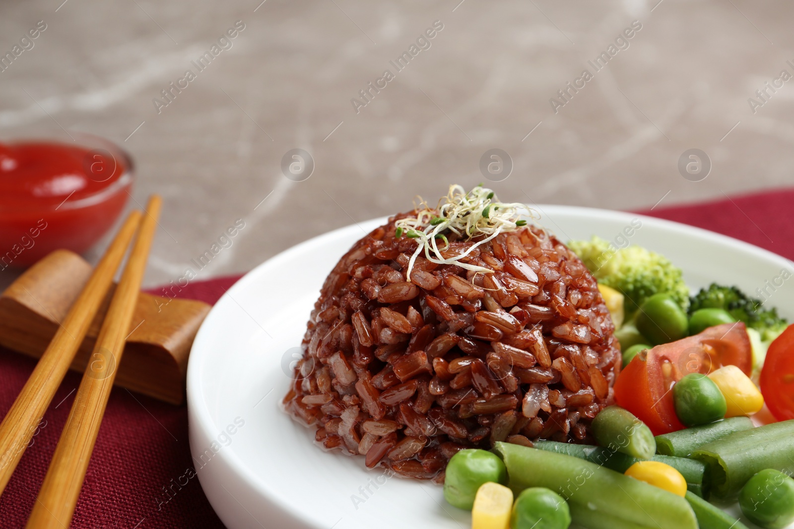 Photo of Plate of boiled brown rice with vegetables served on table, closeup. Space for text