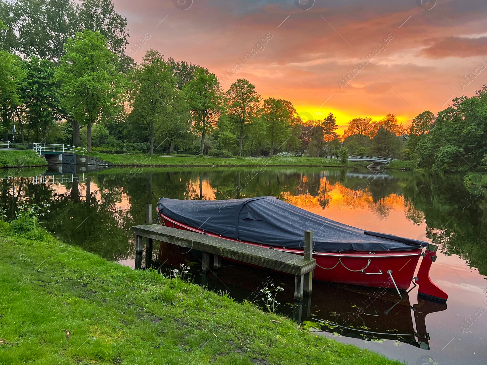 Photo of Scenic view of pond with moored boat at sunset