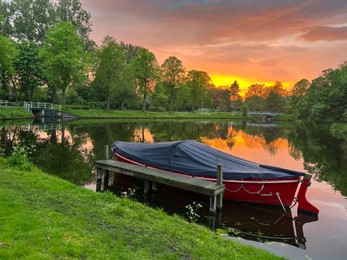 Scenic view of pond with moored boat at sunset