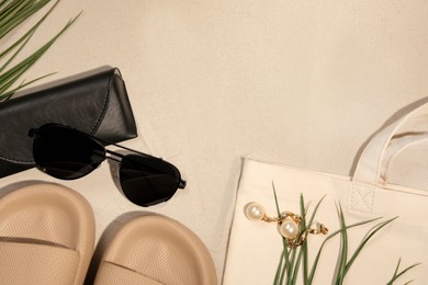 Photo of Flat lay composition with stylish sunglasses and black leather case on sand. Space for text