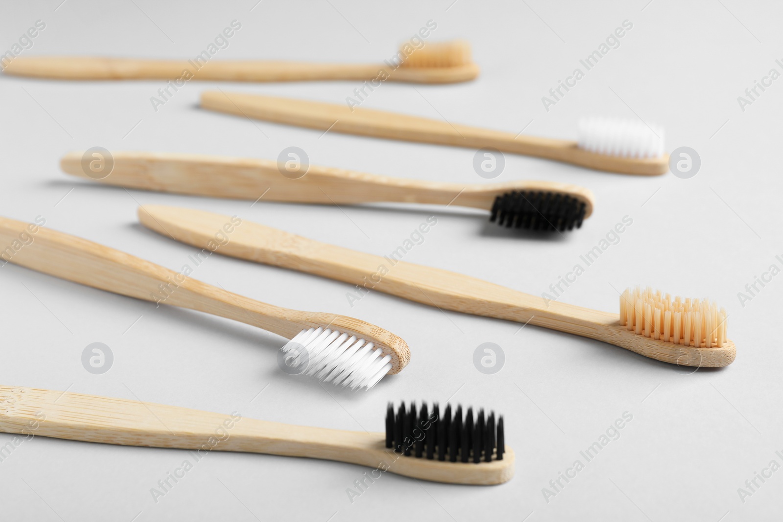 Photo of Many different bamboo toothbrushes on white background